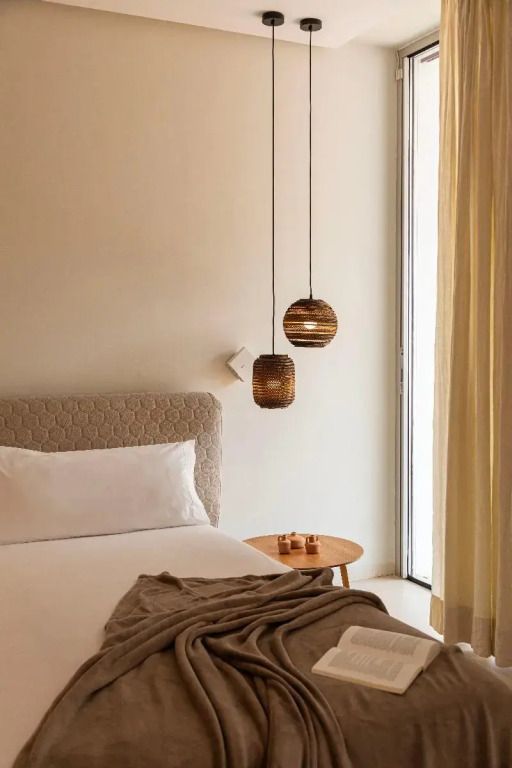 Helles Schlafzimmer mit großem Fenster, Bett und dekorativen Hängelampen