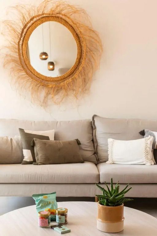 Elegantes Wohnzimmer mit beigem Sofa, Kissen und dekorativem Spiegel an der Wand