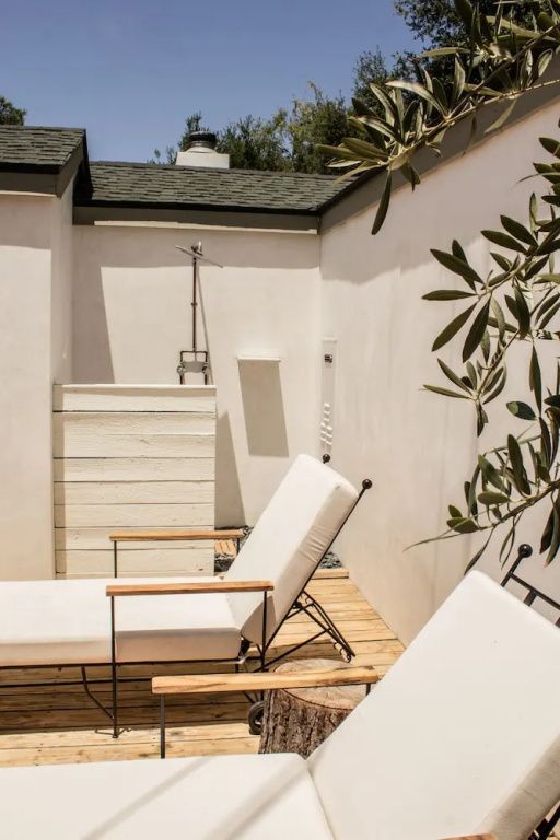 Privater Außenbereich mit Liegestühlen und weißer Wand