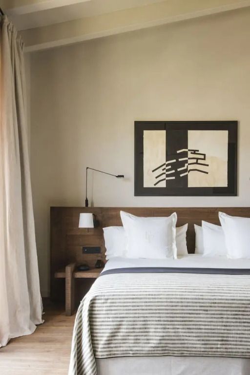 Komfortables Doppelbett mit hellen Kissen und moderner Wandkunst im Hintergrunde.