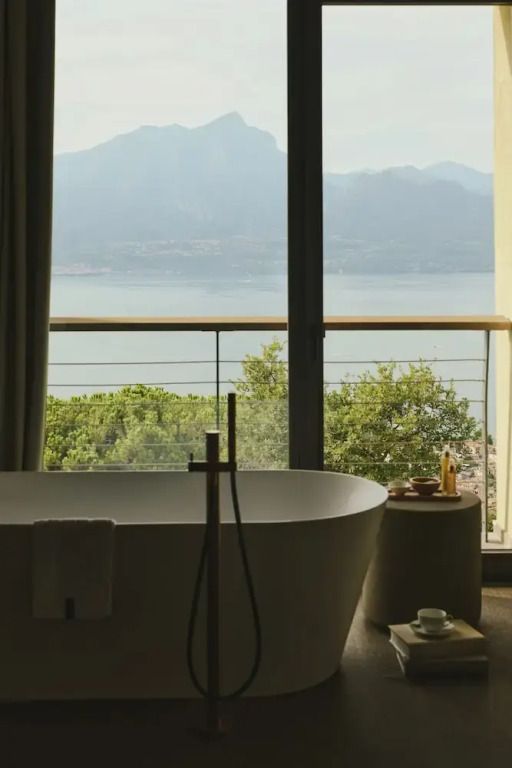 Freistehende Badewanne mit Blick auf den See durch große Fensterfront
