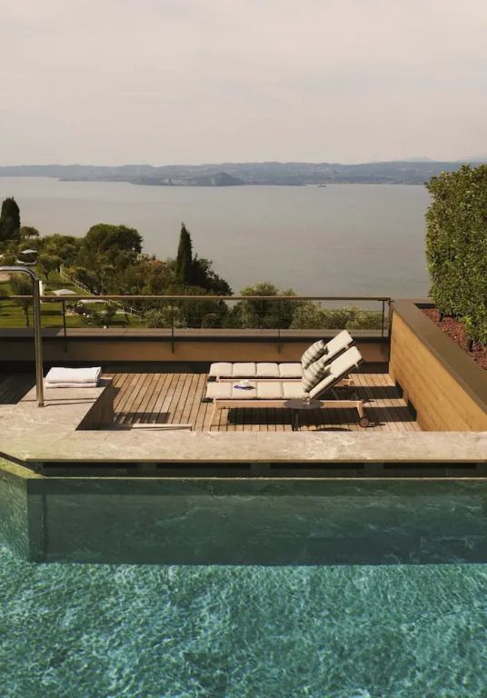 Privater Poolbereich mit Liegestühlen und Blick auf den See