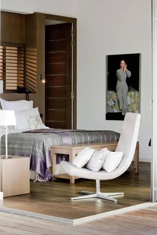 Schickes Schlafzimmer mit moderner Kunst und Designerstuhl