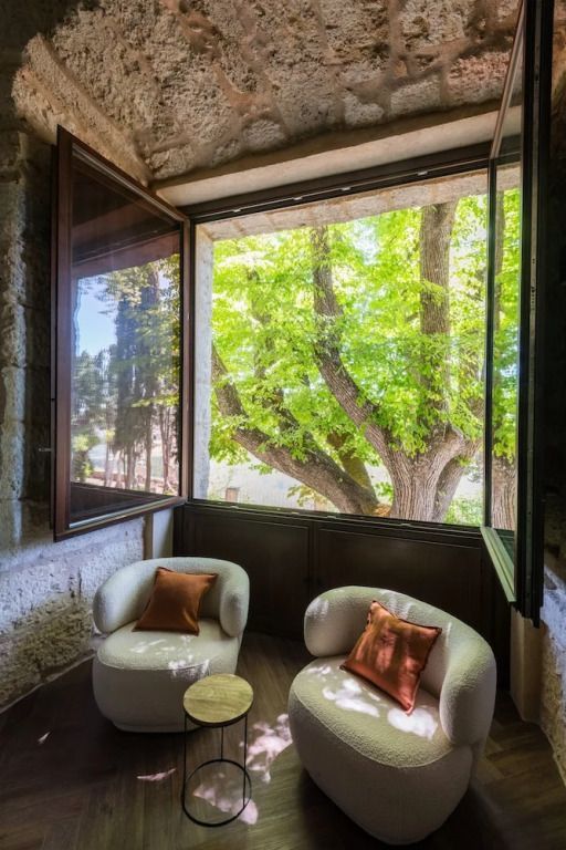 Gemütliche Sitzecke mit zwei Sesseln und Blick auf grünen Baum durch großes Fenster