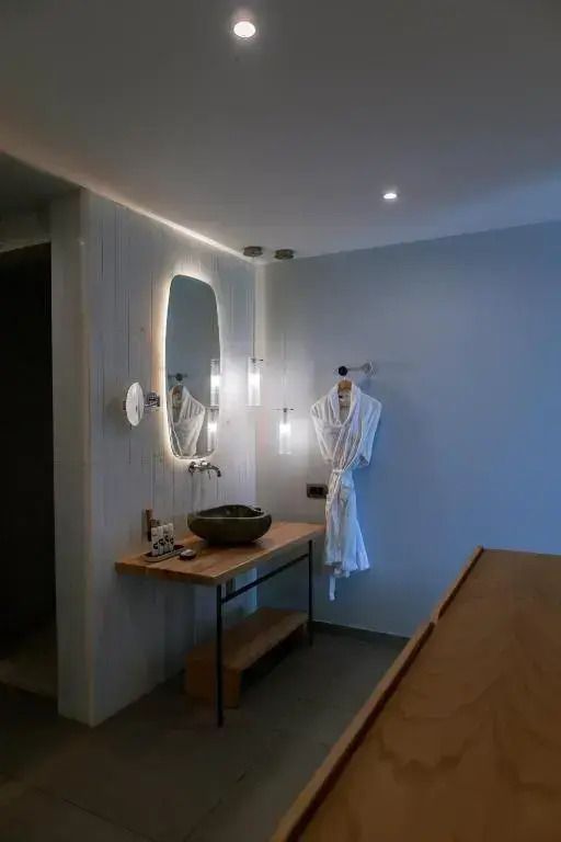 Elegantes Badezimmer mit beleuchtetem Spiegel und hölzerner Ablage