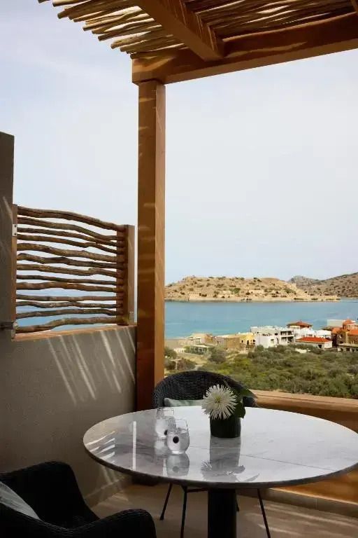 Terrasse mit Meerblick und kleinem Tisch, umgeben von natürlichen Elementen.