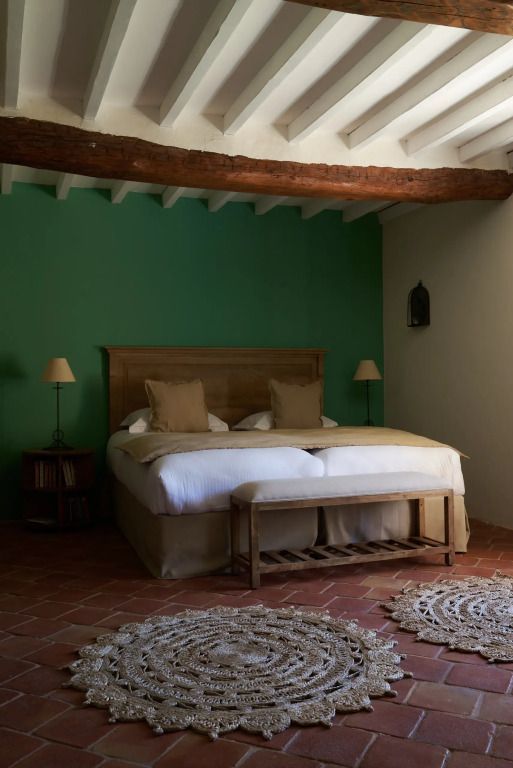 Schlafzimmer mit grün gestrichener Wand und rustikalem Holzbett.