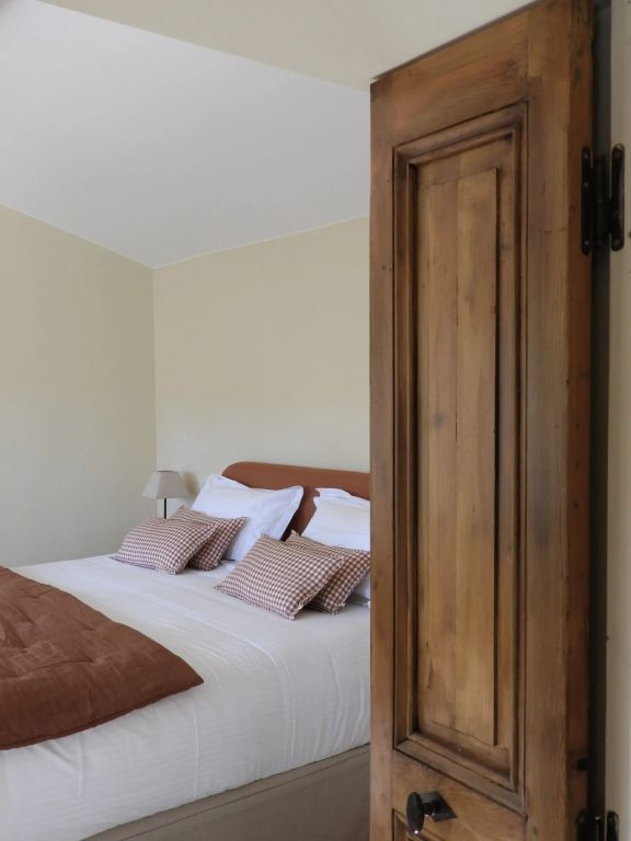 Komfortables Schlafzimmer mit Doppelbett und Holztür in warmen Tönen