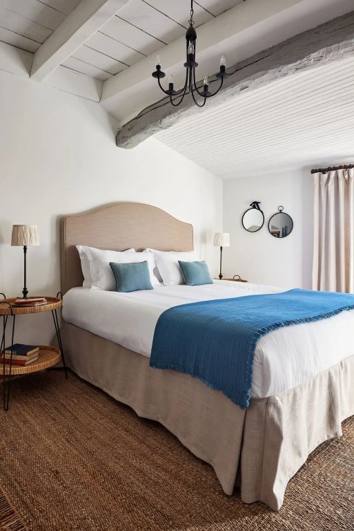 Doppelbett in hellem Zimmer mit rustikalen Akzenten und blauen Details