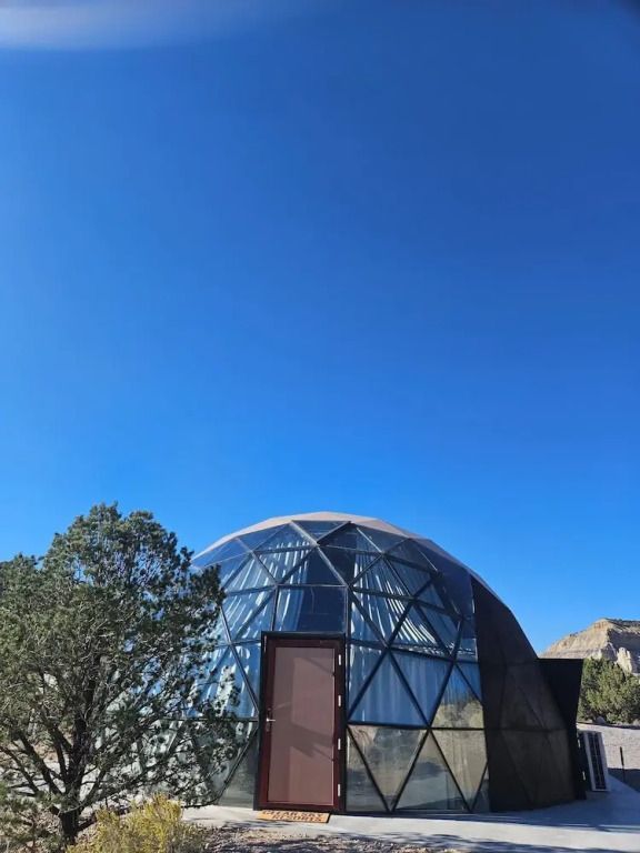 Glaskuppel umgeben von Bäumen unter blauem Himmel