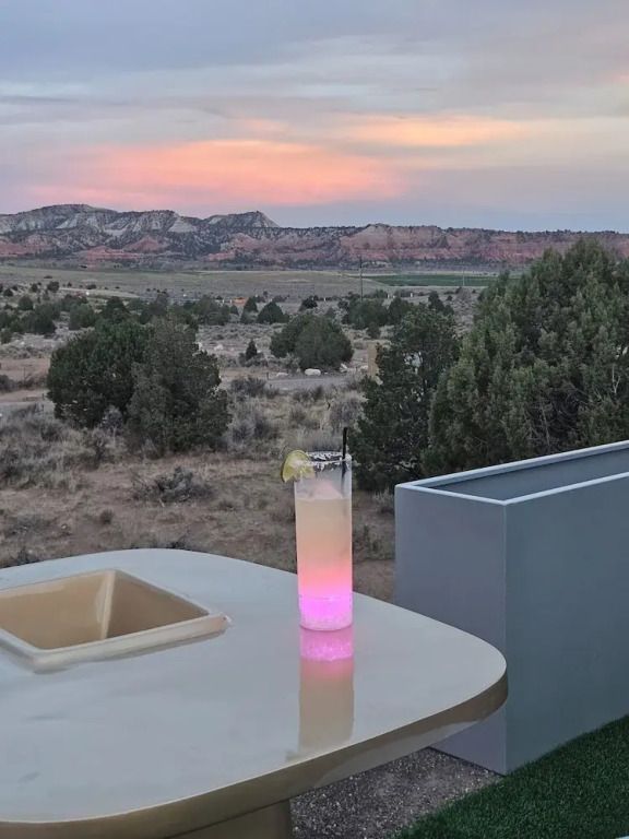 Veranda mit Cocktail und Ausblick auf malerische Wüstenlandschaft bei Sonnenuntergang