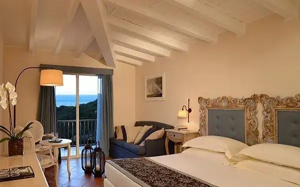 Gemütliches Doppelzimmer mit Sofa und Zugang zu einem Balkon mit Meerblick.