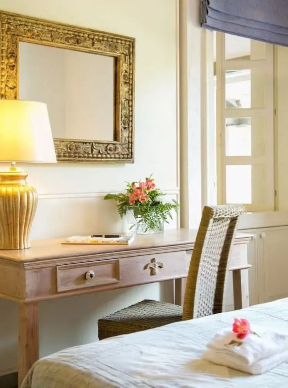 Eleganter Schminktisch mit Spiegel, Lampe und Blumen in einem Hotelzimmer.