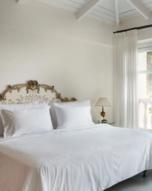 Schlafzimmer mit elegantem Kopfteil und Fenster mit Ausblick auf das Meer.