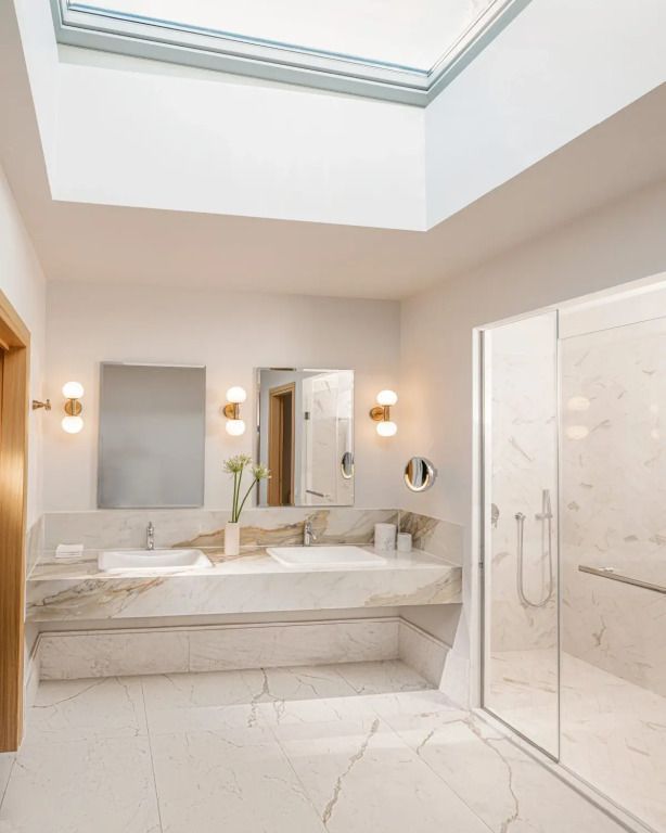 Modernes Badezimmer mit Marmorverkleidung und großen Fenstern