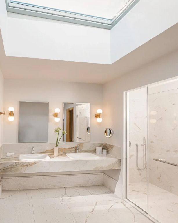 Luxuriöses Badezimmer mit Marmoroberflächen und Oberlicht.