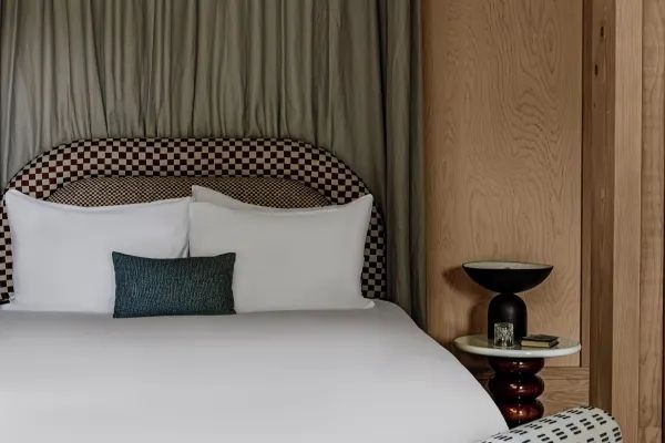 Elegantes Bett mit kariertem Kopfteil und stilvoller Nachtleuchte in einem luxuriösen Hotelzimmer