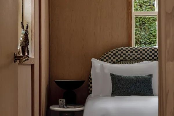 Schlafbereich mit elegantem Kopfteil, Kissen und Wandverkleidung im Hotelzimmer