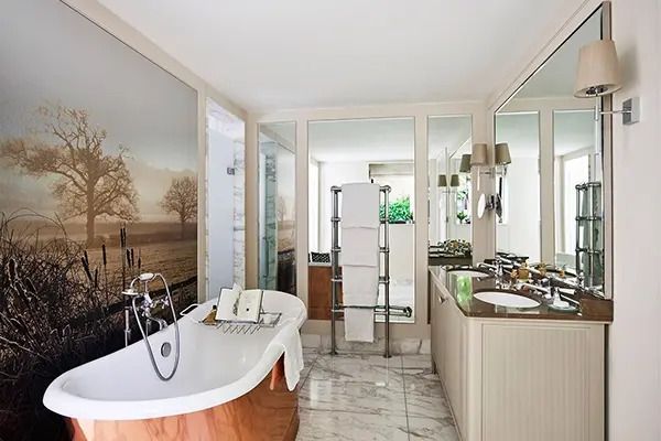 Luxuriöses Badezimmer mit freistehender Badewanne aus Marmor, Doppelwaschbecken und Naturbild