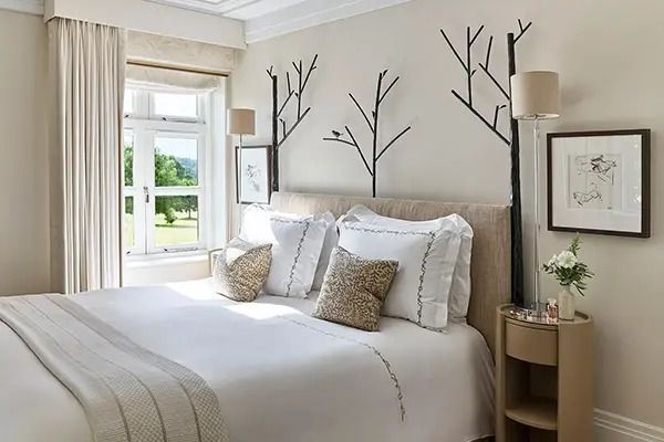 Schlafzimmer mit Doppelbett und stilvollen Baumdekorationen an der Wand