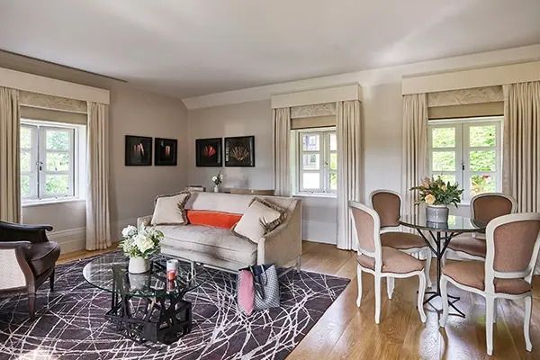 Helle Suite mit Sofa, Tisch, Stühlen und stilvollen Vorhängen