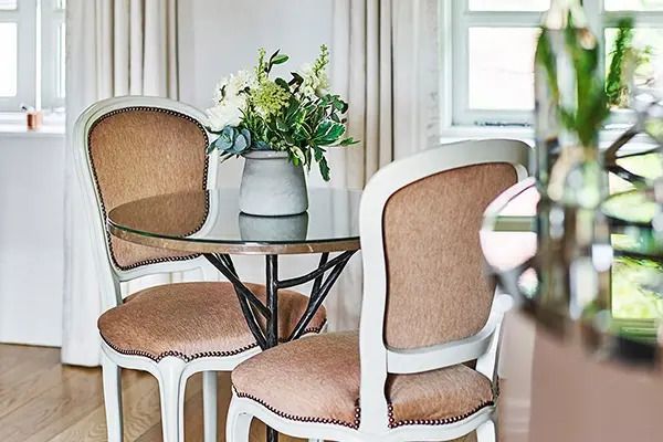 Runder Glastisch mit blumiger Dekoration und vintage Stühlen