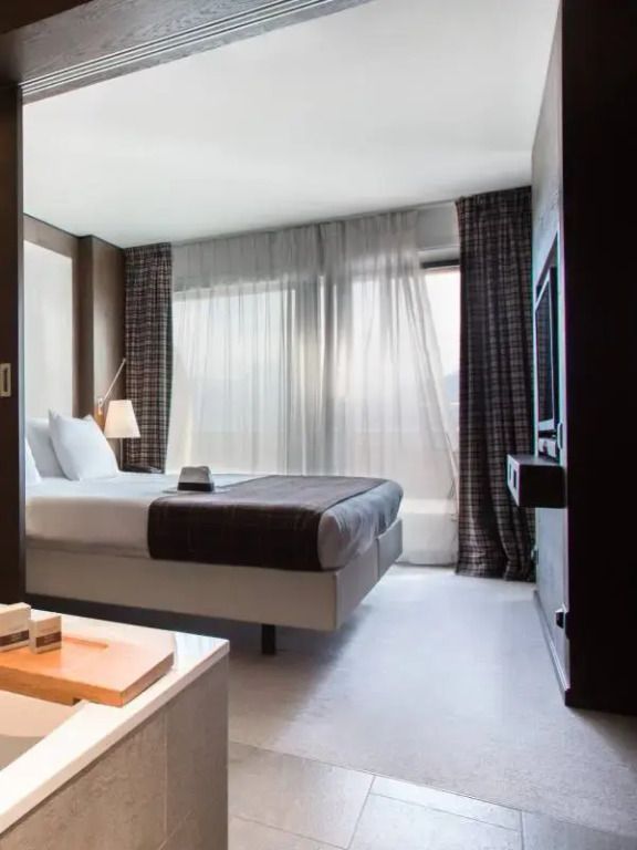 Moderne Alpina Suite mit gemütlichem Bett und großem Fenster mit Bergblick