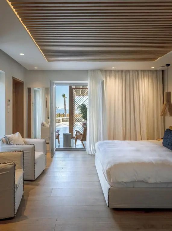 Helles Zimmer mit Doppelbett und Zugang zu einer Terrasse.