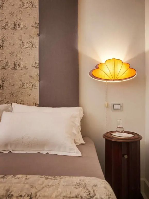 Elegantes Schlafzimmer mit stilvoller Wandlampe und gemütlichem Bett
