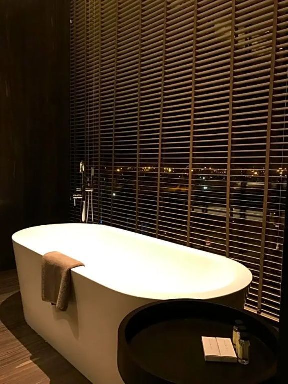 Freistehende Badewanne im Badezimmer der Terrasse Suite mit Blick durch Jalousien