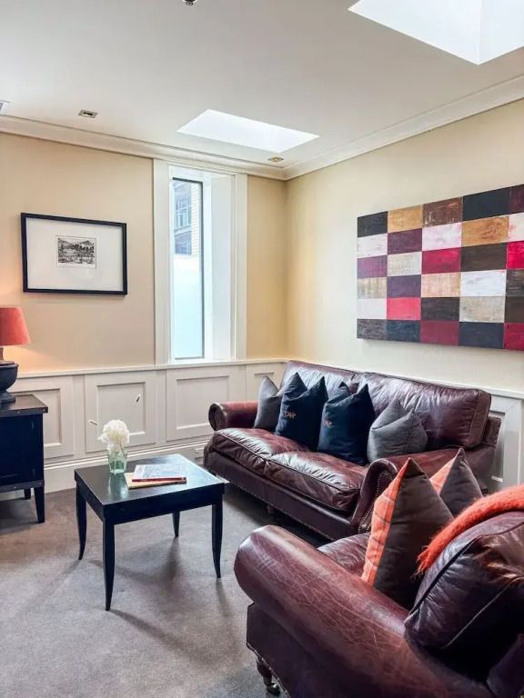 Heller Wohnbereich einer Suite mit Ledersofas und moderner Kunst an der Wand