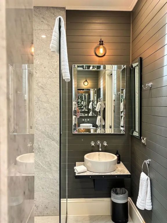 Modernes Badezimmer mit Marmordusche und stilvoll beleuchtetem Spiegel