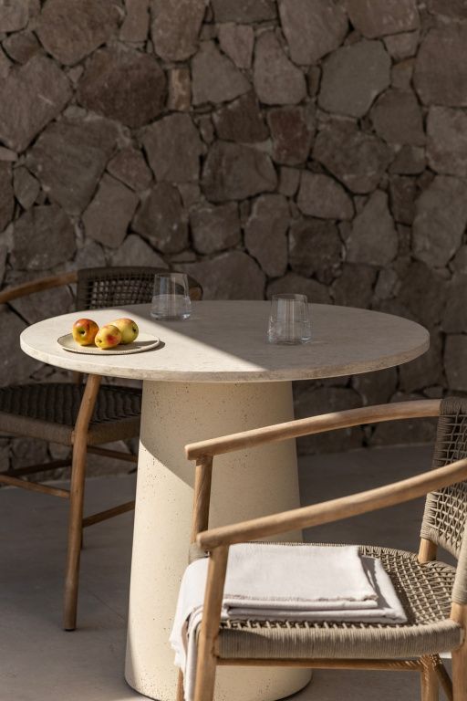 Gemütlicher Außenbereich mit Tisch und Stühlen vor einer Steinmauer