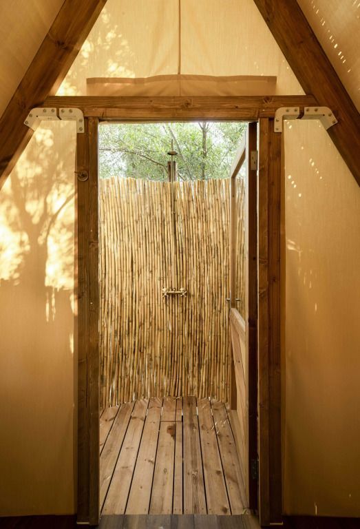 Dusche im Freien mit natürlichem Bambus-Sichtschutz und Holzdetails.