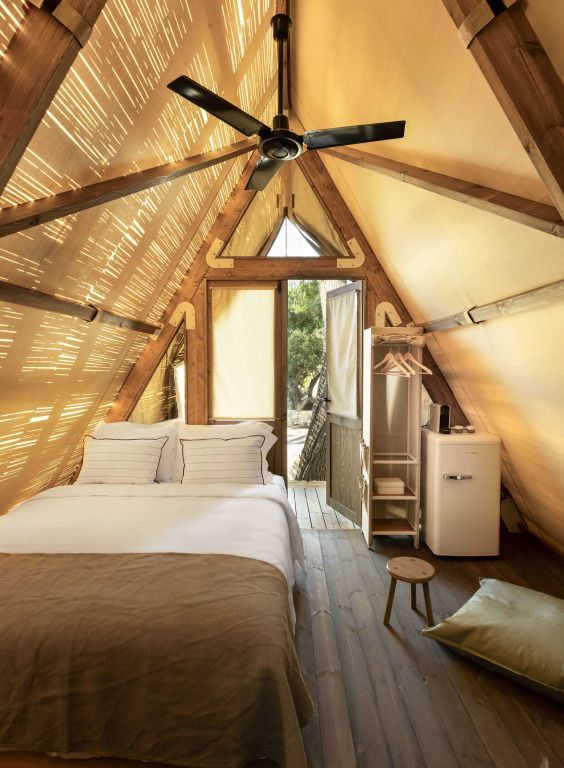 Innenaufnahme eines komfortabel eingerichteten Zeltes mit Bett und Ventilator.