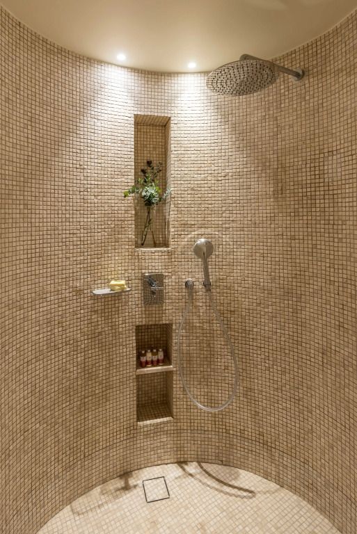 Kunstvoll geflieste Dusche mit eingebauten Ablagen und sanfter Beleuchtung