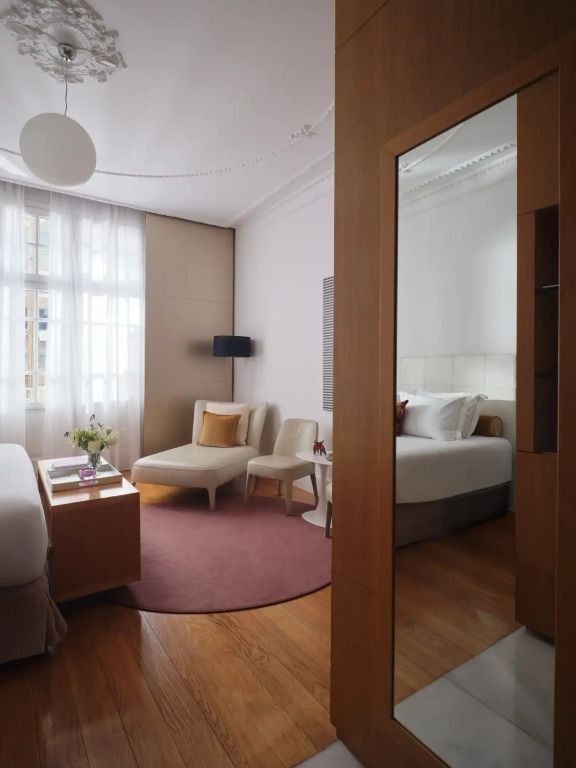 Geräumiges Zimmer mit großem Fenster, Sitzbereich und luxuriösem Bett.
