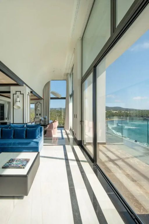 Wohnbereich in der Suite mit Glaswänden und Blick auf das Meer.