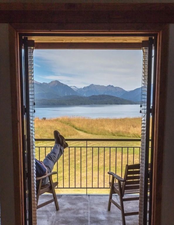 Blick von einem Balkon auf einen See mit Bergen im Hintergrund