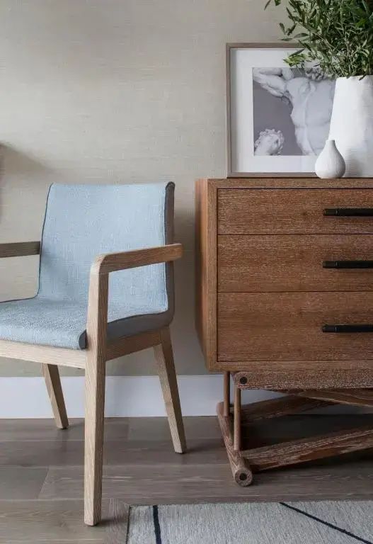 Eleganter hellblauer Sessel und Holzkommode in modern gestaltetem Hotelzimmer.