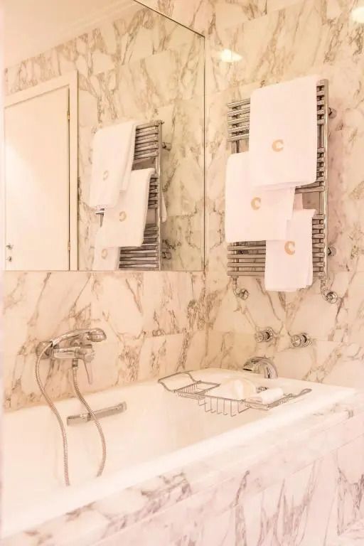 Modernes Badezimmer mit Marmorfliesen und ausgestatteter Badewanne.