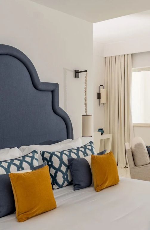 Detailaufnahme eines Bettes mit blauer Kopflehne und bunten Kissen in der Suite