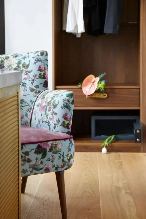 Geblümter Stuhl neben einem Holzbücherregal mit Deko