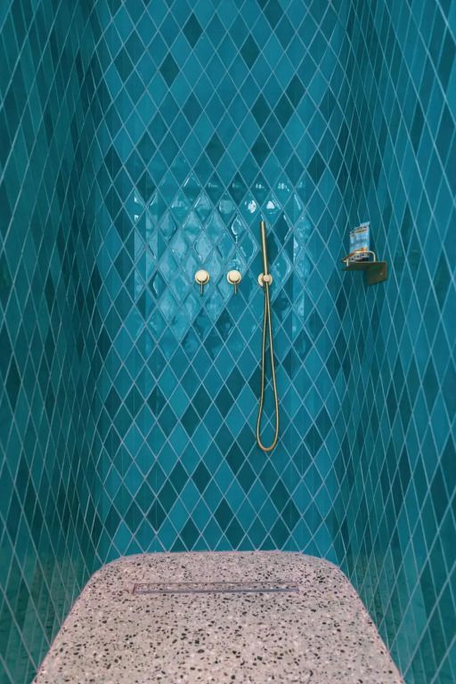 Dusche mit blauen Fliesen und luxuriösen Armaturen