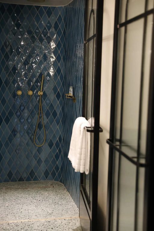 Elegante Dusche mit blauen Fliesen und goldener Armatur in Badezimmer
