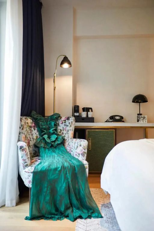 Gemütliche Sitzecke mit Blumenmuster-Sessel und eleganter Tagesdecke im Hotelzimmer