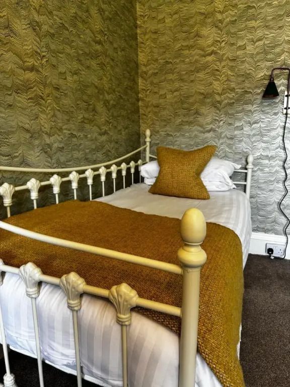 Einzelbett mit senfgelber Decke in elegantem Zimmerdesign
