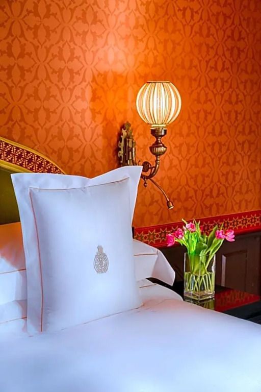 Beleuchtete Nachttischlampe neben einem eleganten Bett mit Blumen