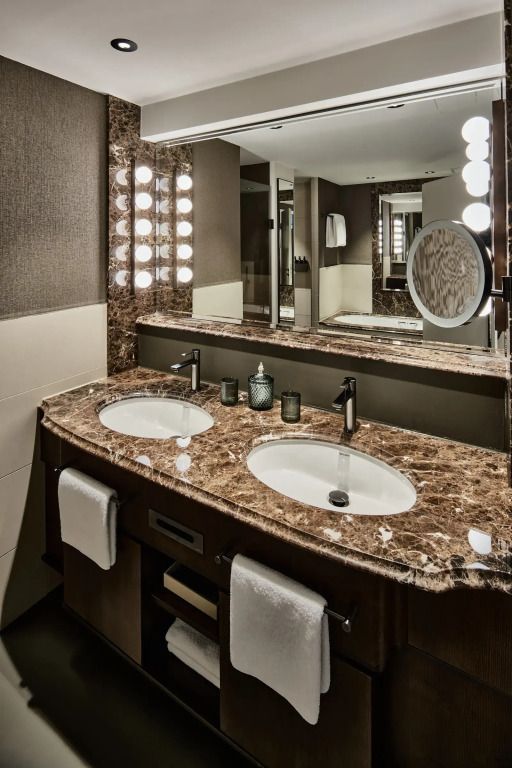 Elegantes Badezimmer im Hotel mit Marmordoppelwaschbecken und stilvollen Leuchten