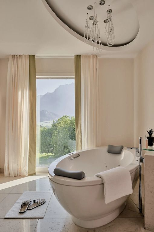 Freistehende Badewanne im Badezimmer mit Blick auf die Natur durch das Fenster